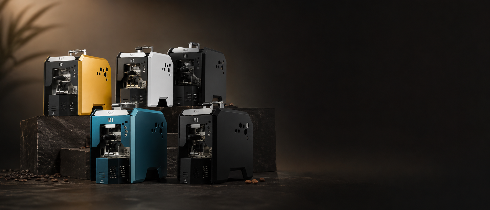 Premium Kaleido home coffee roasters displayed on dark stone plinths in a polished editorial coffee studio setting, with warm lighting and generous negative space.