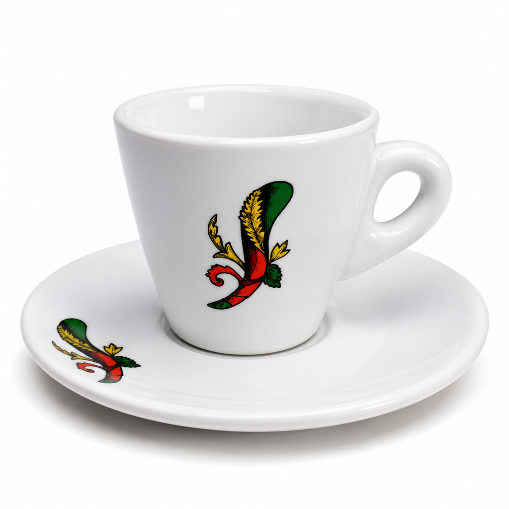 A white ceramic espresso cup with a matching saucer, both decorated with a colorful traditional tattoo-style bird design in green, red, yellow, and black.