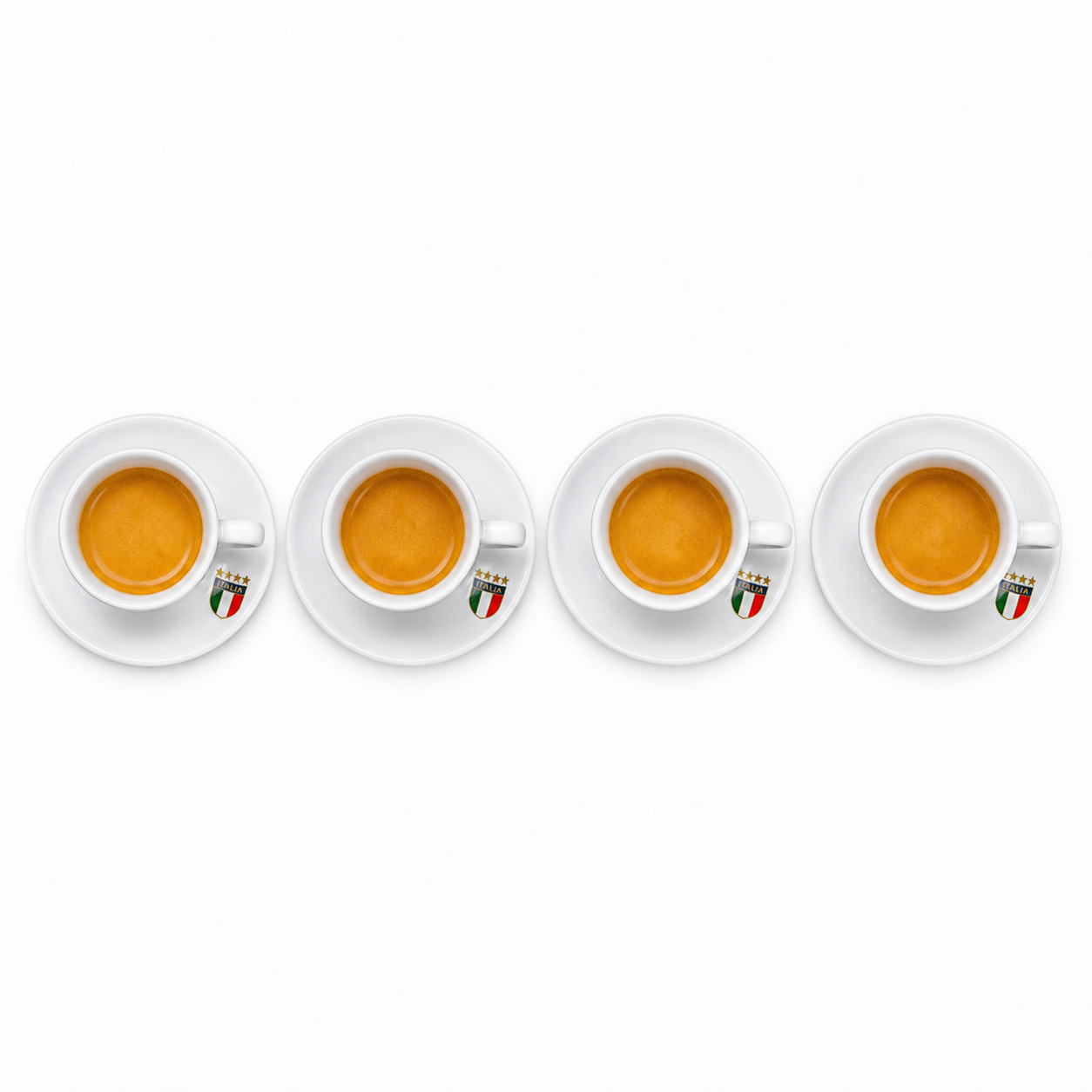 Four white ceramic espresso cups with saucers, each filled with espresso and featuring a small Italian flag emblem on the side, arranged in a row on a white background.