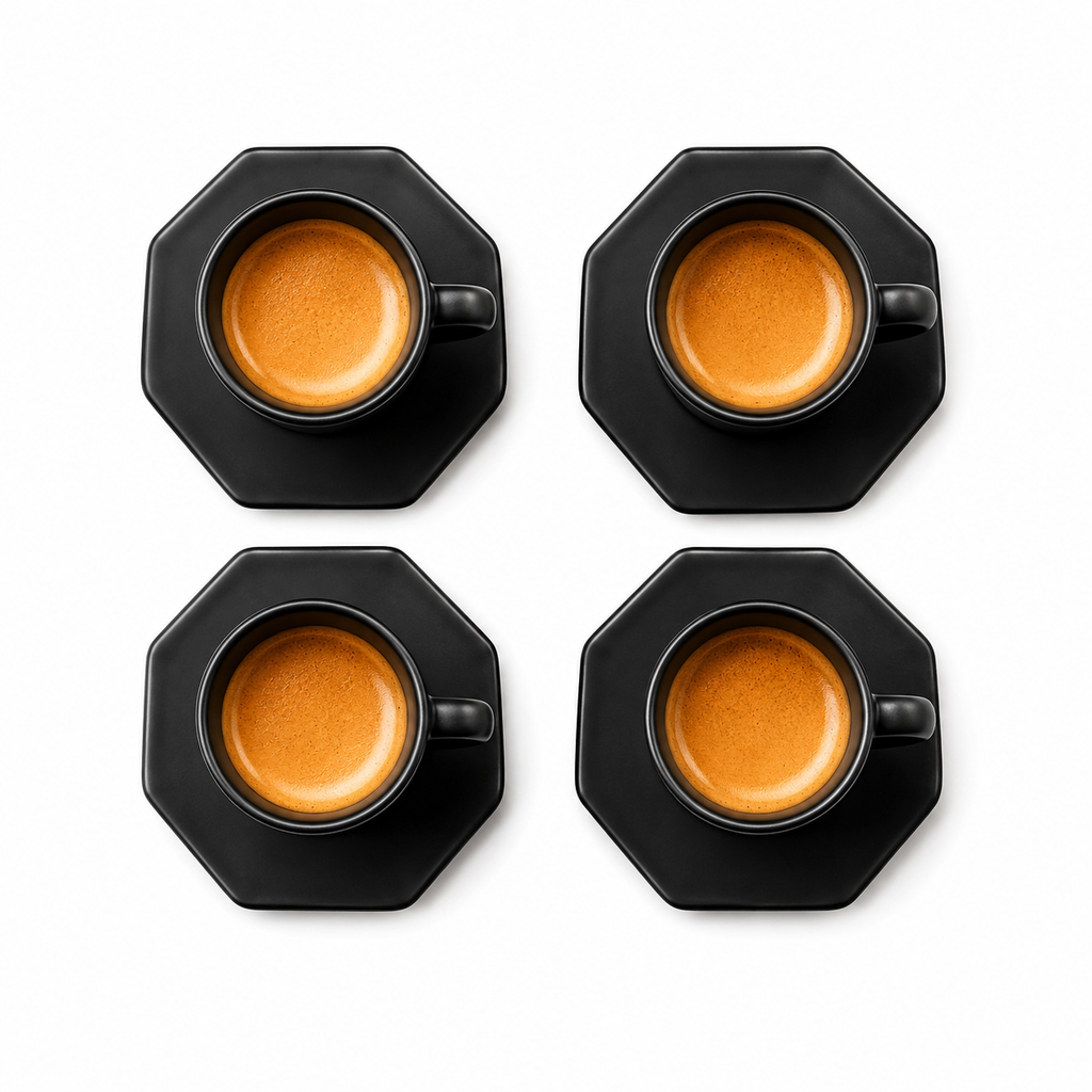 Four black octagonal coffee cups with matching saucers, each filled with espresso and topped with a layer of milk foam, arranged in a 2x2 grid on a white background.